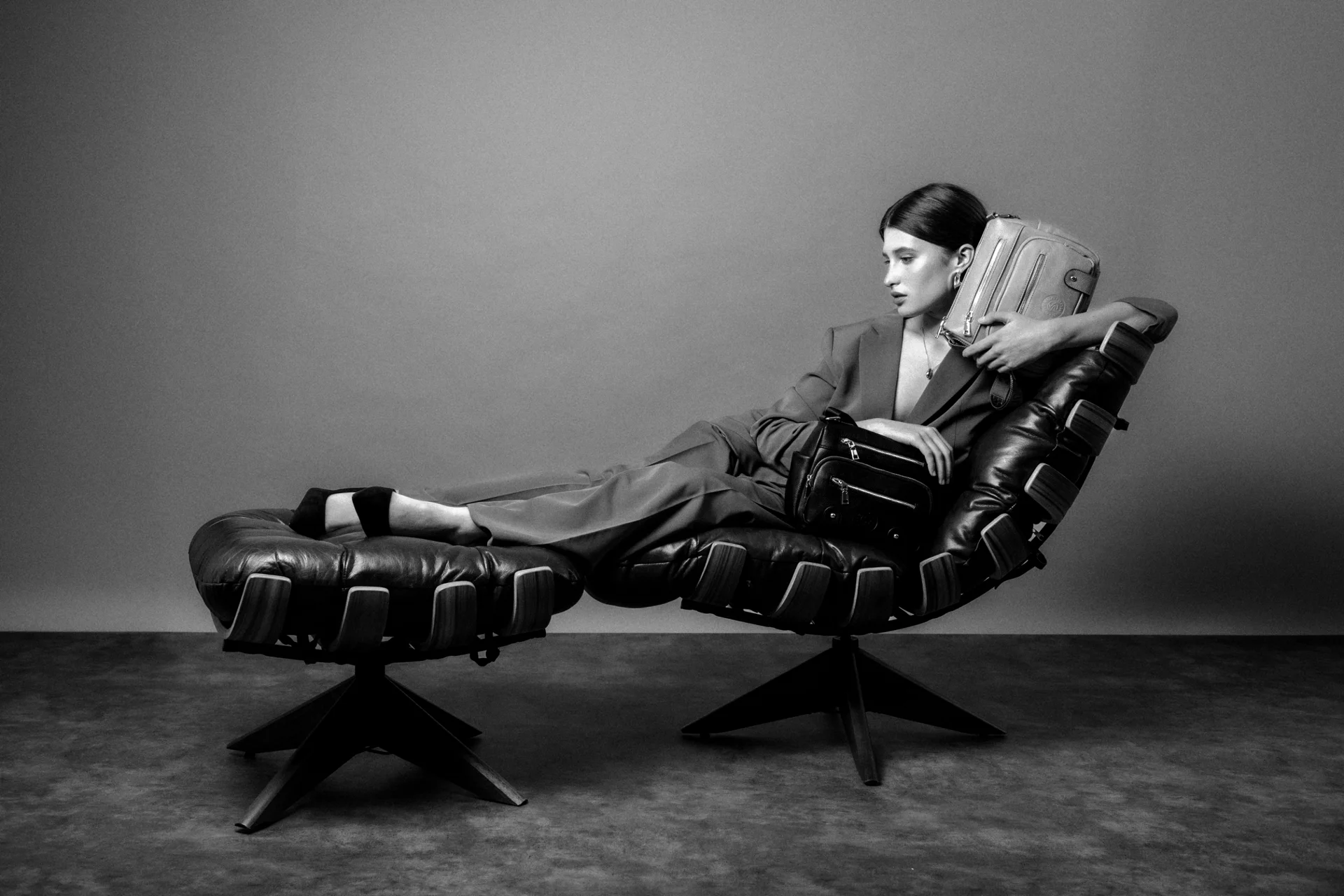 Producción de moda en blanco y negro: modelo recostada en una silla de diseño